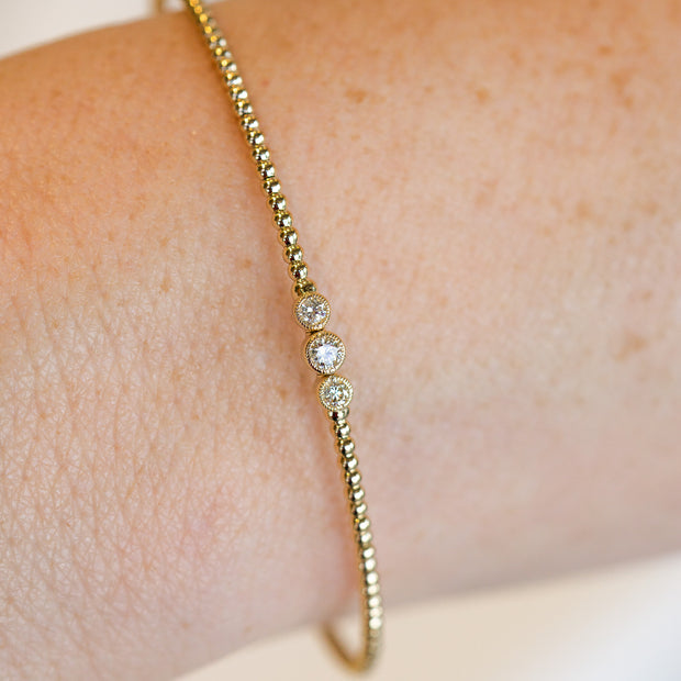 14K Yellow Gold 0.16ct Round Bezel Diamond Trio Flexible Beaded Bangle Bracelet. Bichsel Jewelry in Sedalia, MO. Shop gold and diamond jewelry online or in-store!